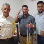 tres integrantes de la delegación muestran sus medallas y trofeos