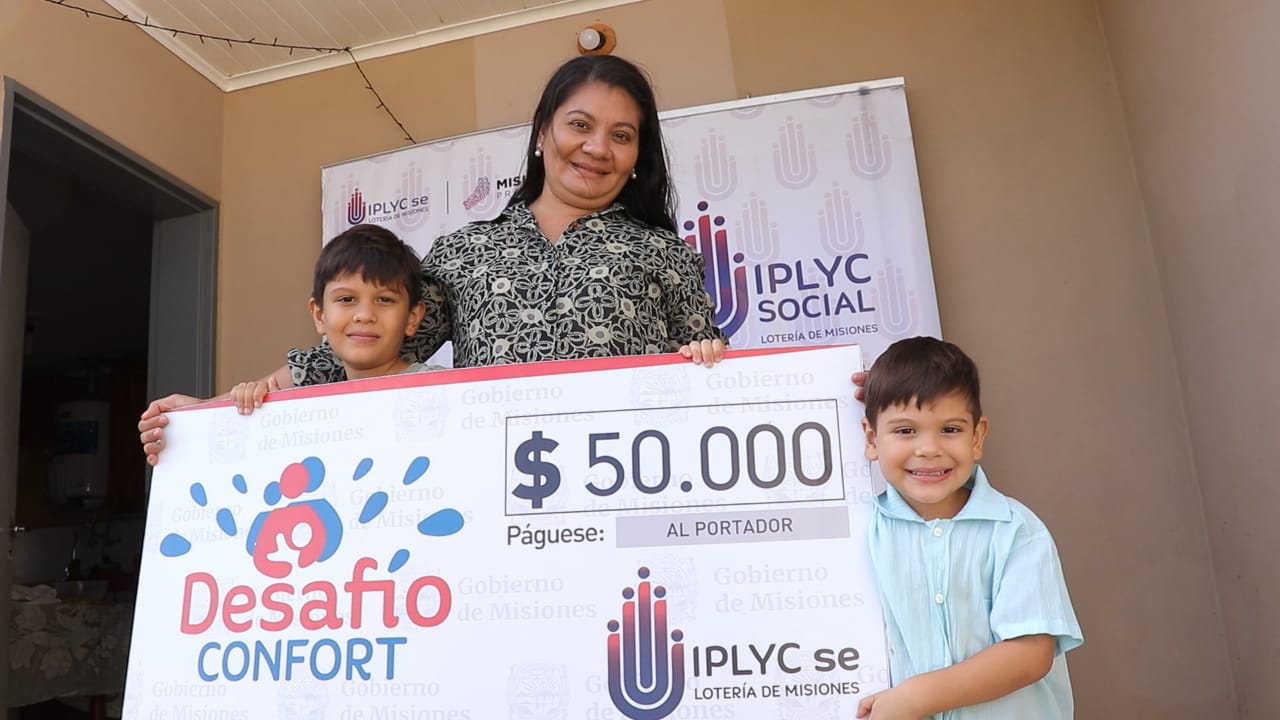 Analía Ferreira junto a sus dos hijos, muestra felíz su cheque.