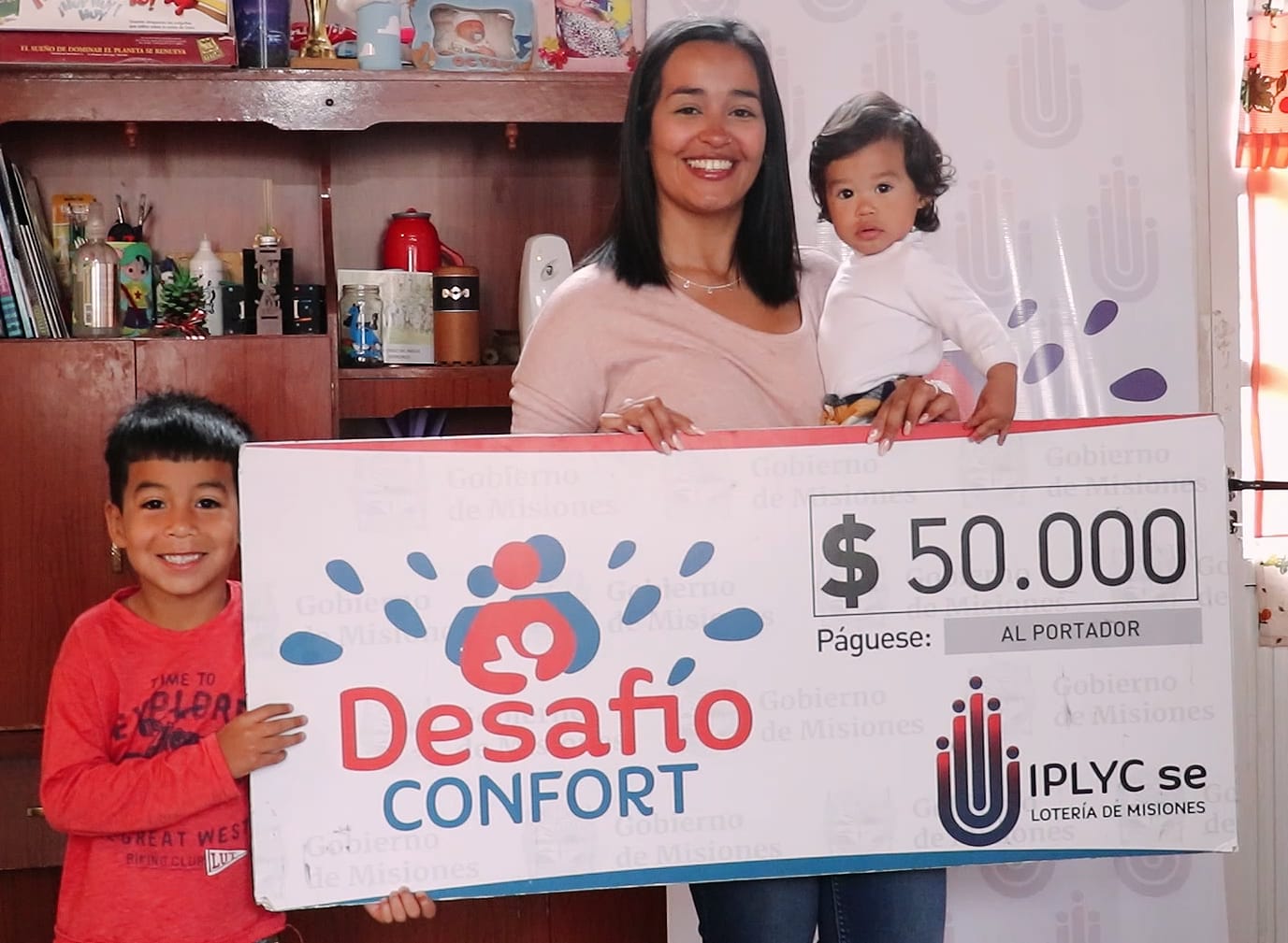 ganadora recibe el cheque con sus dos hijos