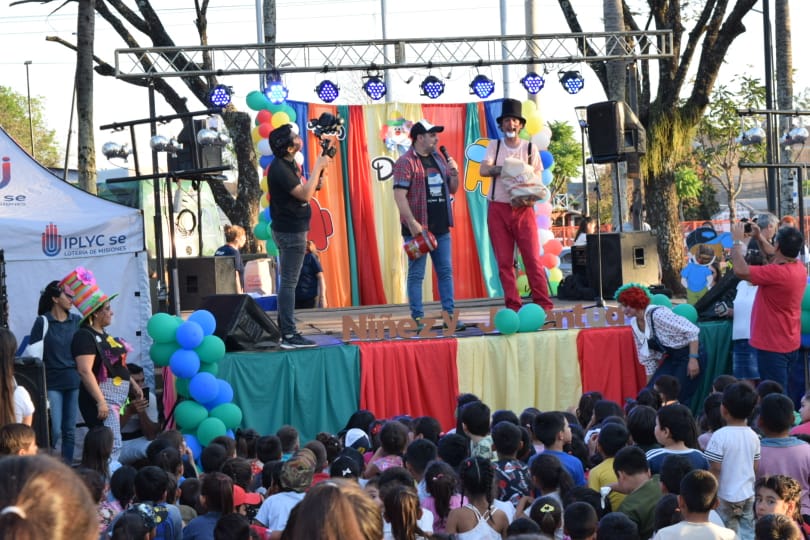 El equipo de Gurises en el escenario frente a los niños mientras el payaso Poca Sopa realiza un sorteo