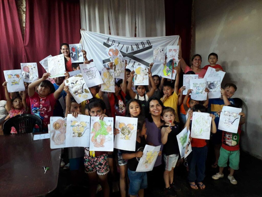 Mabel Pezoa junto a los niños que participaron mostrando sus dibujos