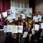 Mabel Pezoa junto a los niños que participaron mostrando sus dibujos