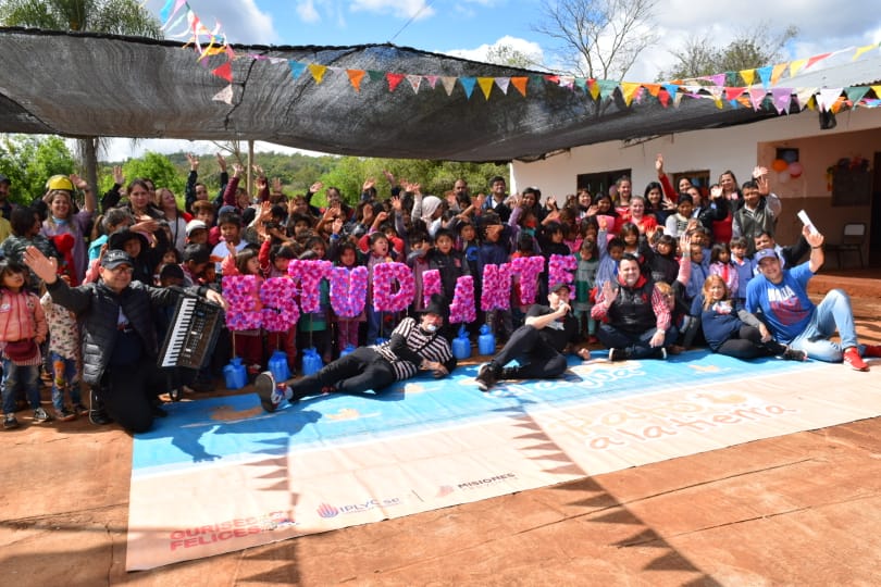 equipo de Gurises y los niños de la escuela saludan a la cámara.