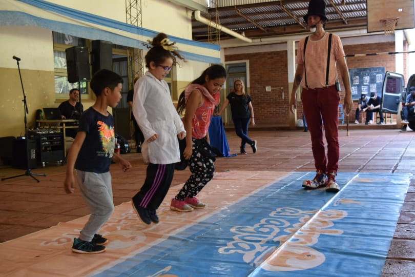 Tres niños saltando sobre un juego de piso con el payaso Poca Sopa.
