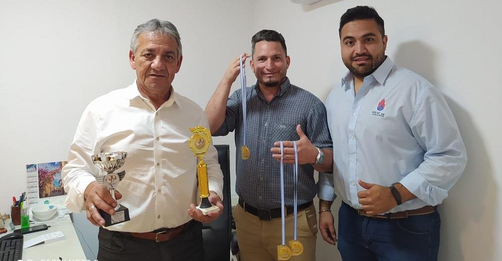 tres integrantes de la delegación muestran sus medallas y trofeos