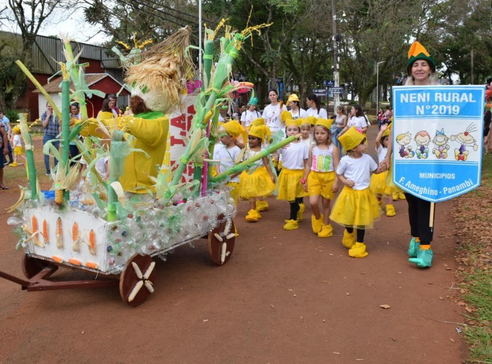 mini carroza secundada por los niños con trajes amarillos y blancos, y el estandarte de NENI Rural