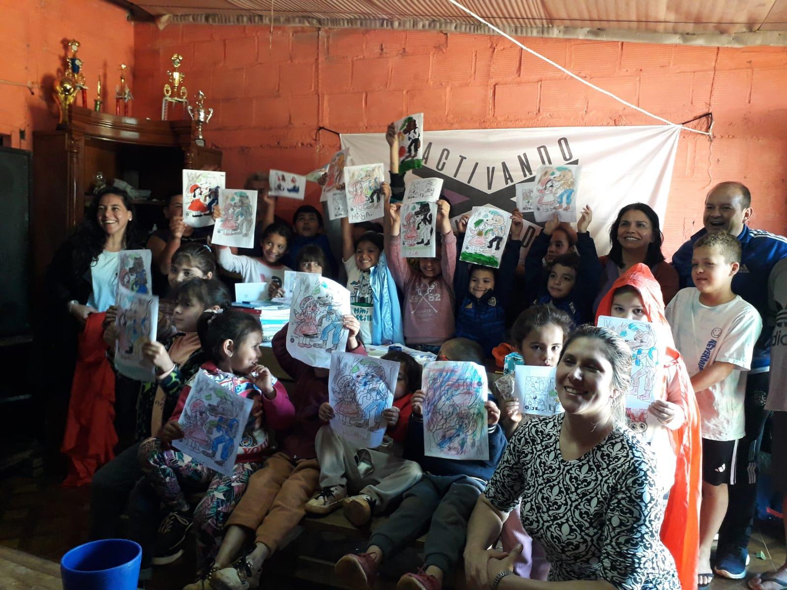 los niños muestran en alto sus dibujos acompañados por Raquel González y el equipo de Activando Voluntades