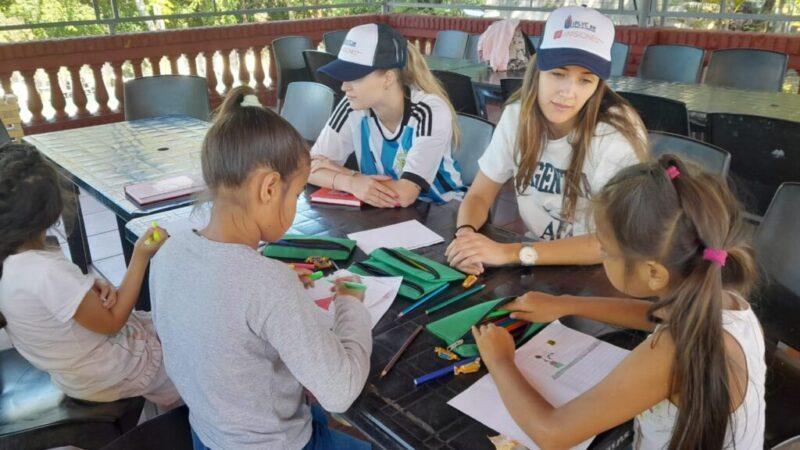 niños dibujando junto a colaboradores del programa