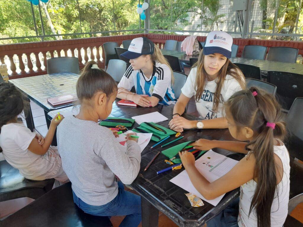 niños dibujando junto a colaboradores del programa