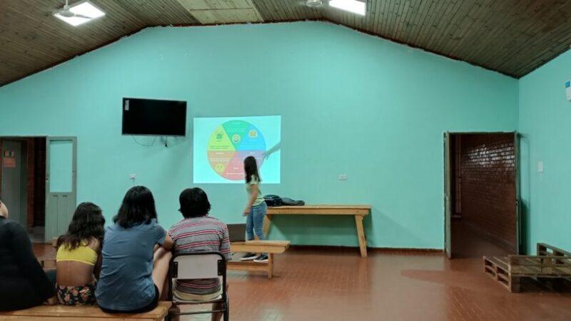 psicóloga del equipo de Juego Responsable explica un gráfico estadístico a jóvenes del hogar Papa Francisco.