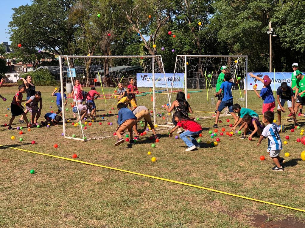 niños jugando con pelotitas de colores y arcos en una cancha