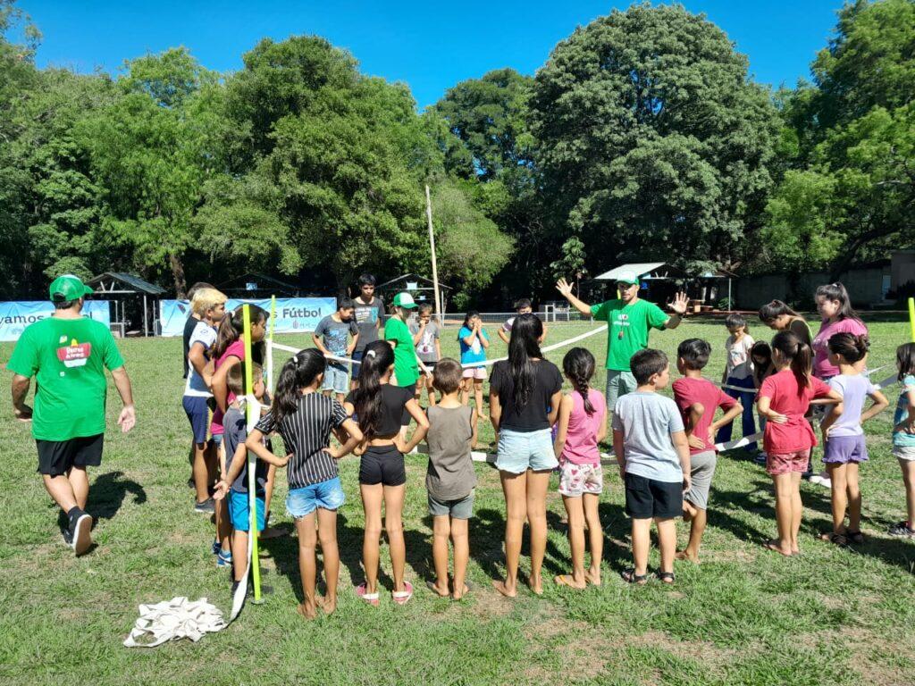 niños en ronda por empezar un juego, escuchan atentos indicaciones del coordinador