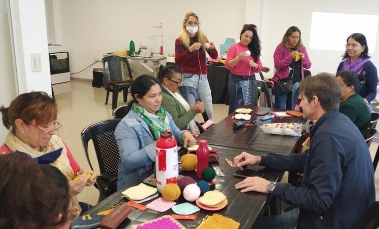 Héctor Decut charla con las voluntarias mientras tejen