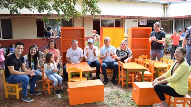 niños, docentes e integrantes de IPLyC Social sonríen y aplauden sentados en el mobiliario escolar