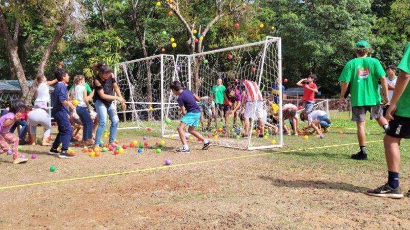 dos equipos de niños compiten en juego con pelotitas de colores y arcos