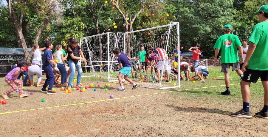 dos equipos de niños compiten en juego con pelotitas de colores y arcos