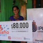 María Castro muestra su cheque frente a su casa