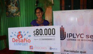 María Castro muestra su cheque frente a su casa