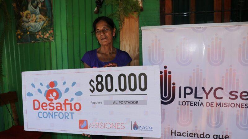 María Castro muestra su cheque frente a su casa