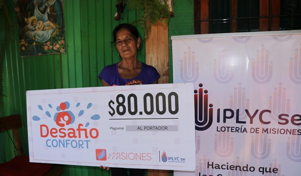 María Castro muestra su cheque frente a su casa