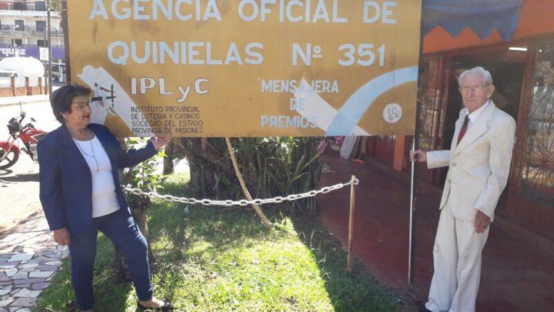 Kusy Ceslao y su esposo frente al cartel de su agencia.