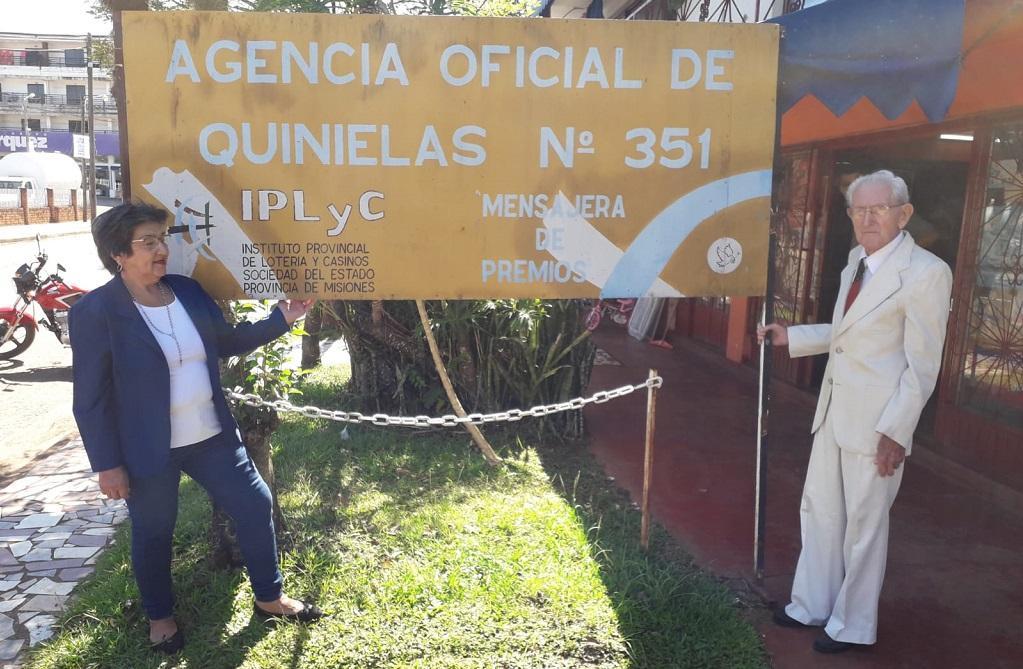 Kusy Ceslao y su esposo frente al cartel de su agencia.