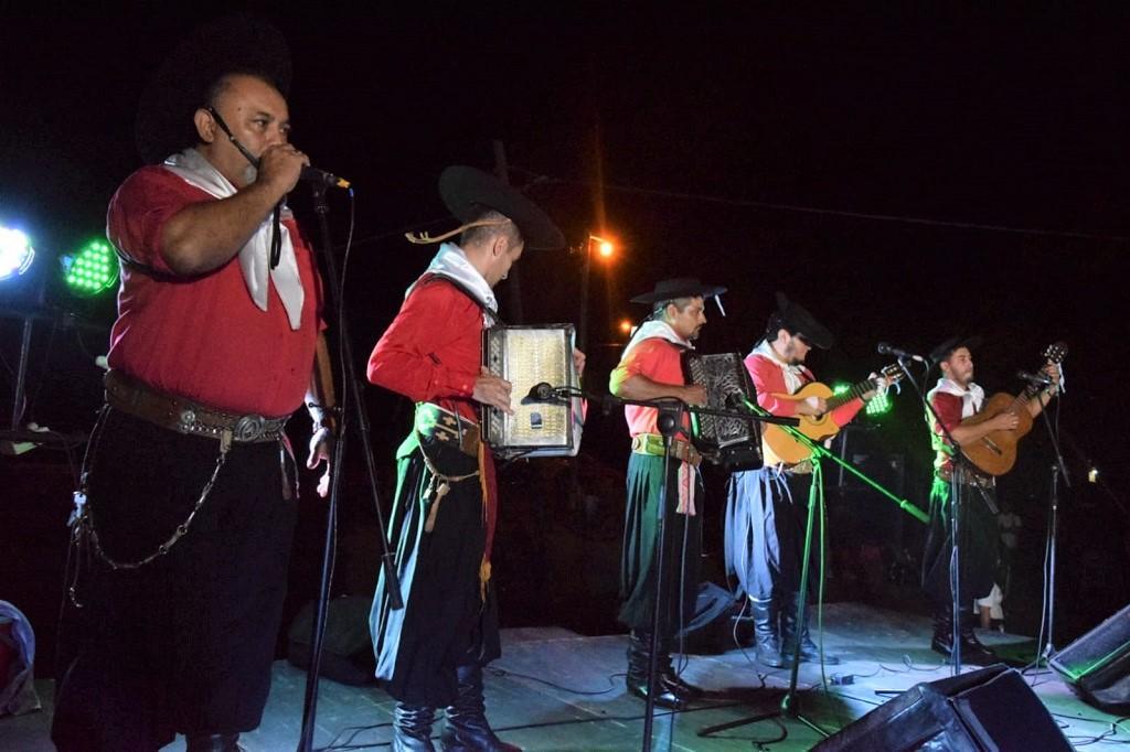 grupo folclórico de 5 integrantes vestidos de gauchos actúa sobre el escenario