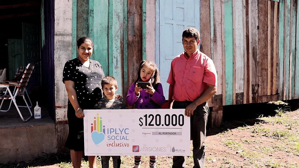 Julia De Olivera junto a su hermanito y sus papás muestran su cheque de IPLyC Inclusivo.