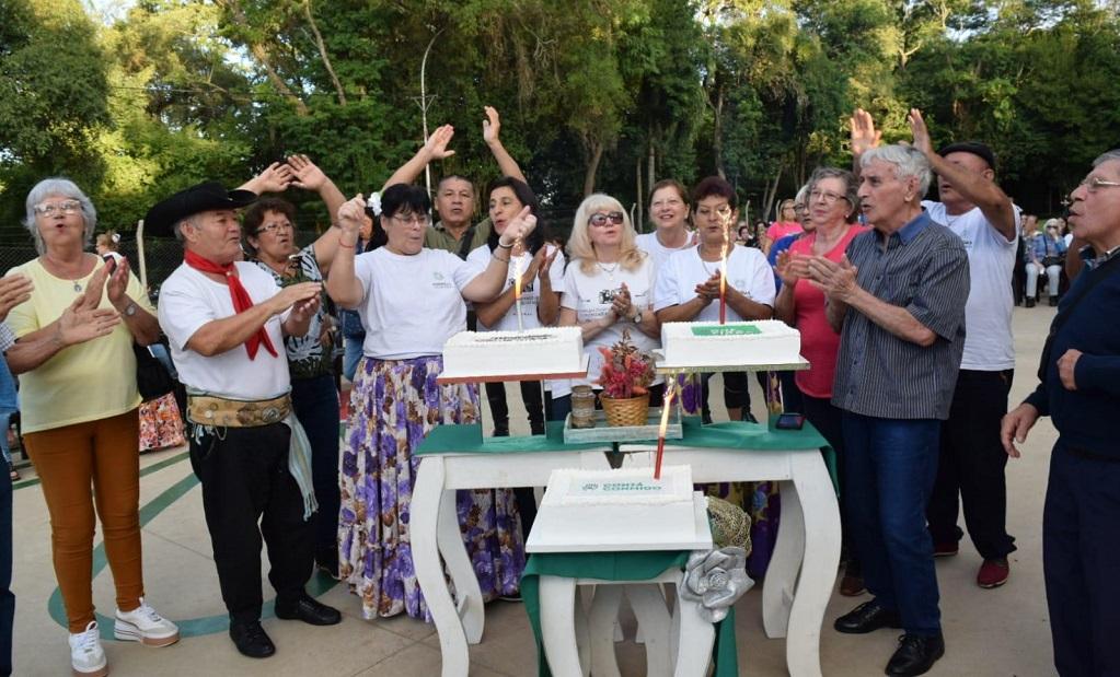 vecinos aplauden alrededor de una mesa con tortas con velitas encendida en el encuentro de mateando con los abuelos.