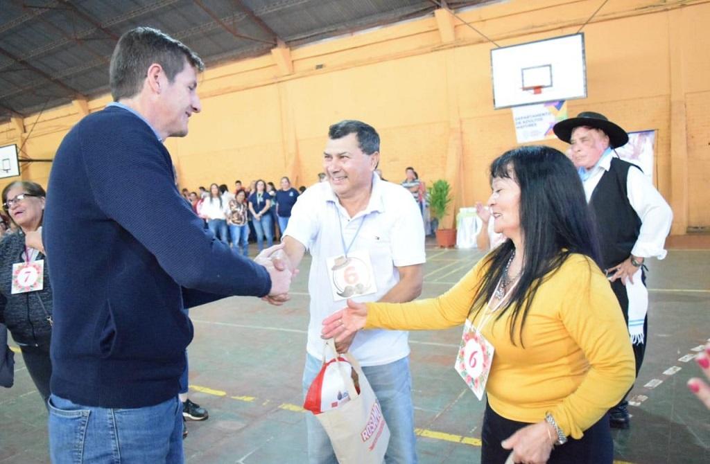 Héctor Decut entrega obsequios a dos participantes del encuentro de abuelos.