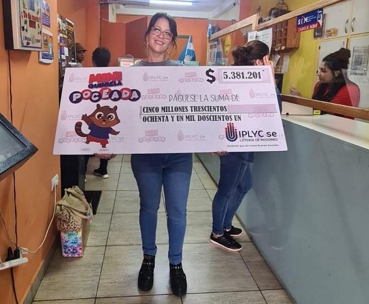 vendedora de la Mini Poceada millonaria en la sub agencia muestra sonriente el cheque