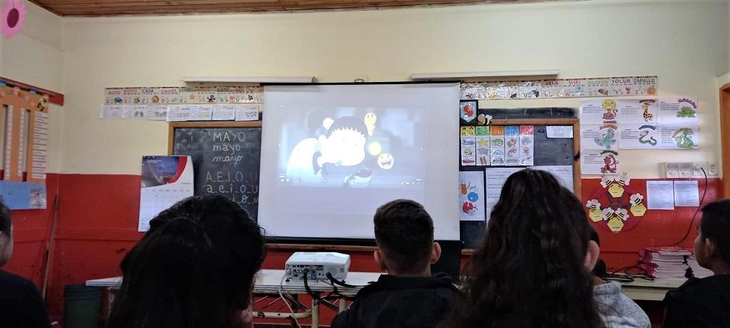 alumnos de la escuela 680 miran proyección de video durante la charla de prevención de adicciones.