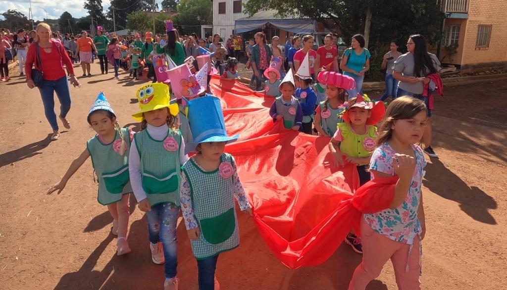 niños de Jardín con guardapolvo y sombreros temáticos desfilan junto a docentes y padres.
