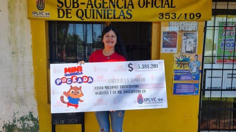 vendedora de la Mini Poceada millonaria frente a la sub agencia muestra sonriente el cheque