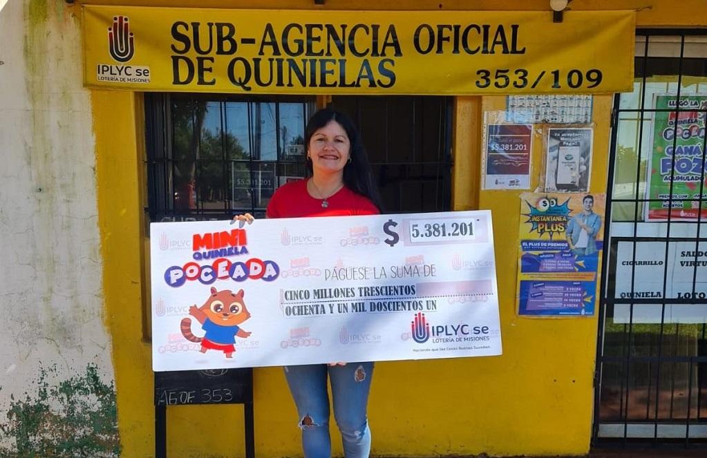 vendedora de la Mini Poceada millonaria frente a la sub agencia muestra sonriente el cheque