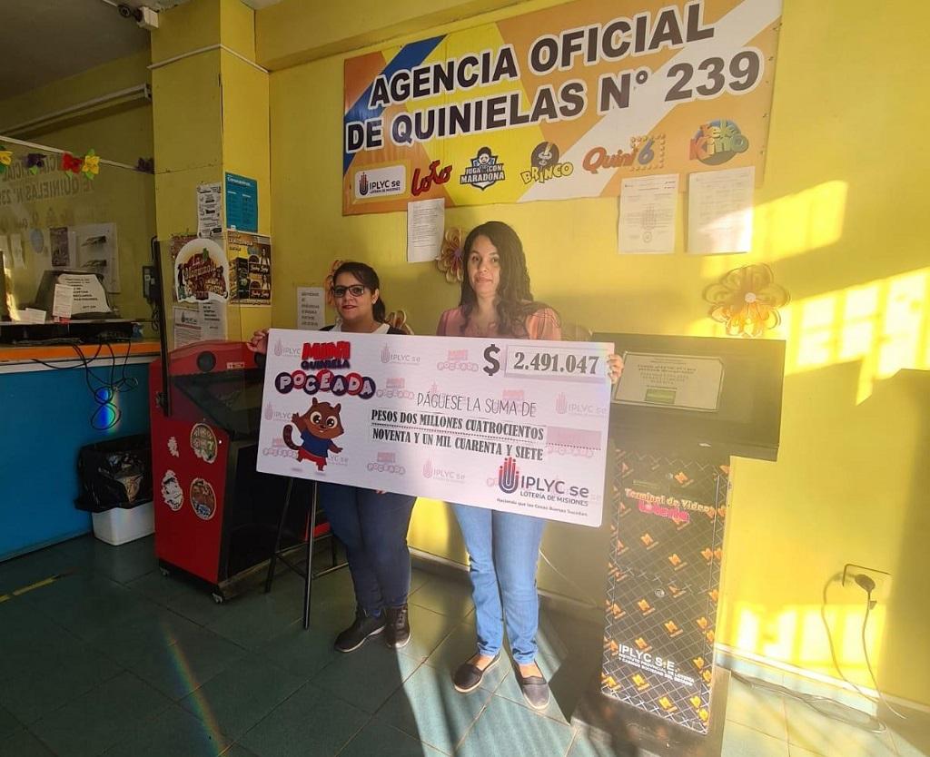 Raquel Moreira y Natalia Munaretto muestran cheque gigante del primer premio de la Mini Poceada, en el local de la Agencia.