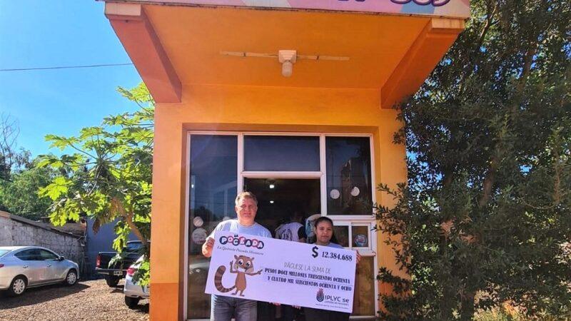 Jorge Zubczuk junto a una joven muestran el cheque del premio de la Poceada frente a su agencia.