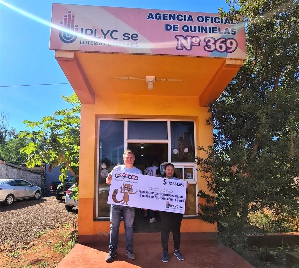 Jorge Zubczuk junto a una joven muestran el cheque del premio de la Poceada frente a su agencia.