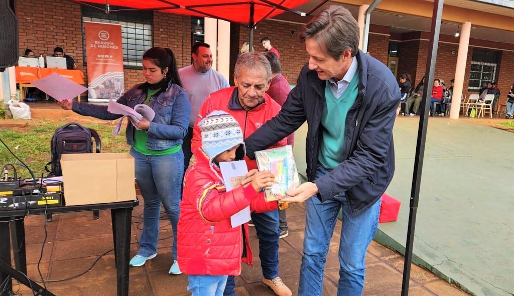 Héctor Decut entrega un libro a un niño que se acercó al operativo de IPLyC Social Presente