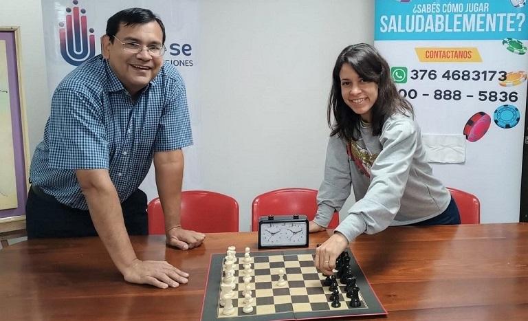 Un organizador del torneo junto a la titular de Juego Responsable muestran uno de los tableros de ajedrez.