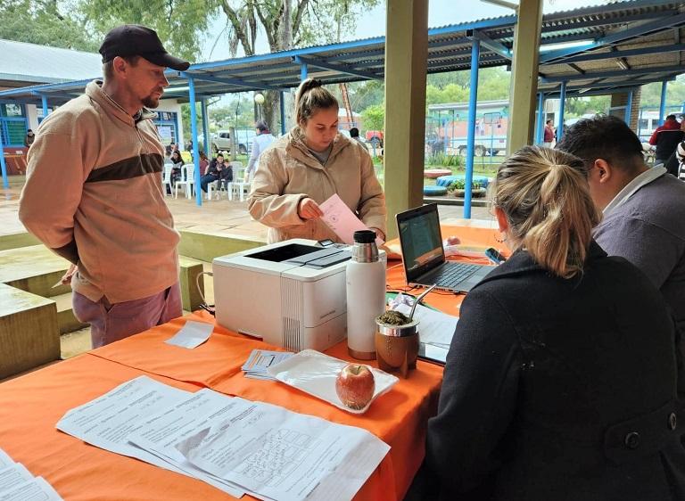 Dos vecinos que se acercaron al operativo de servicios integrales reciben asesoramiento de colaboradores de Energía de Misiones (EMSA).