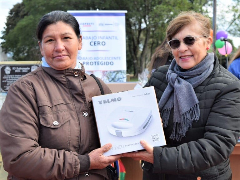 Ganadora de un sorteo recibe su premio (un pequeño electrodoméstico), entregado por una colaboradora de IPLyC Social.