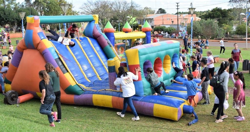 Niñños jugando en un castillo inflable en la plaza, festejando el mes de la infancia.