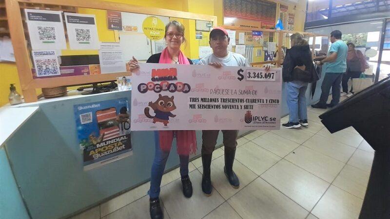 Julio Vera, vendedor que armó la jugada del ticket ganador de la Mini Poceada junto a la encargada de la Agencia 353, muestran el cheque en el local.