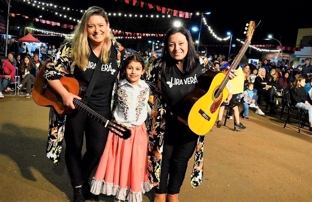 Integrantes de Lira Verá con sus guitarras y niña con traje típico folklórico.
