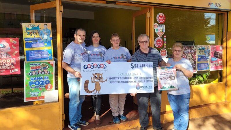 Equipo de la Agencia 316, frente al local, muestra sonriente el cheque del premio millonario de la Poceada Misionera.
