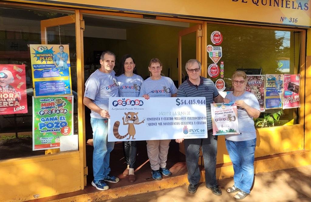 Equipo de la Agencia 316, frente al local, muestra sonriente el cheque del premio millonario de la Poceada Misionera.