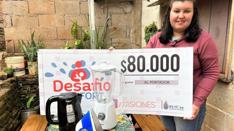 Natalia Da Silva, ganadora de Desafío Confort, muestra sonriente su cheque y electrodomésticos del premio.