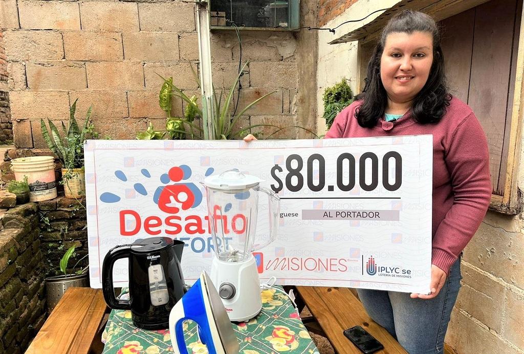 Natalia Da Silva, ganadora de Desafío Confort, muestra sonriente su cheque y electrodomésticos del premio.