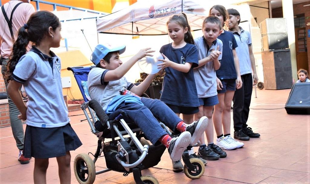 Grupo de niños participan de un juego en equipo de pase de pelota, formando una fila, en el patio de la escuela.